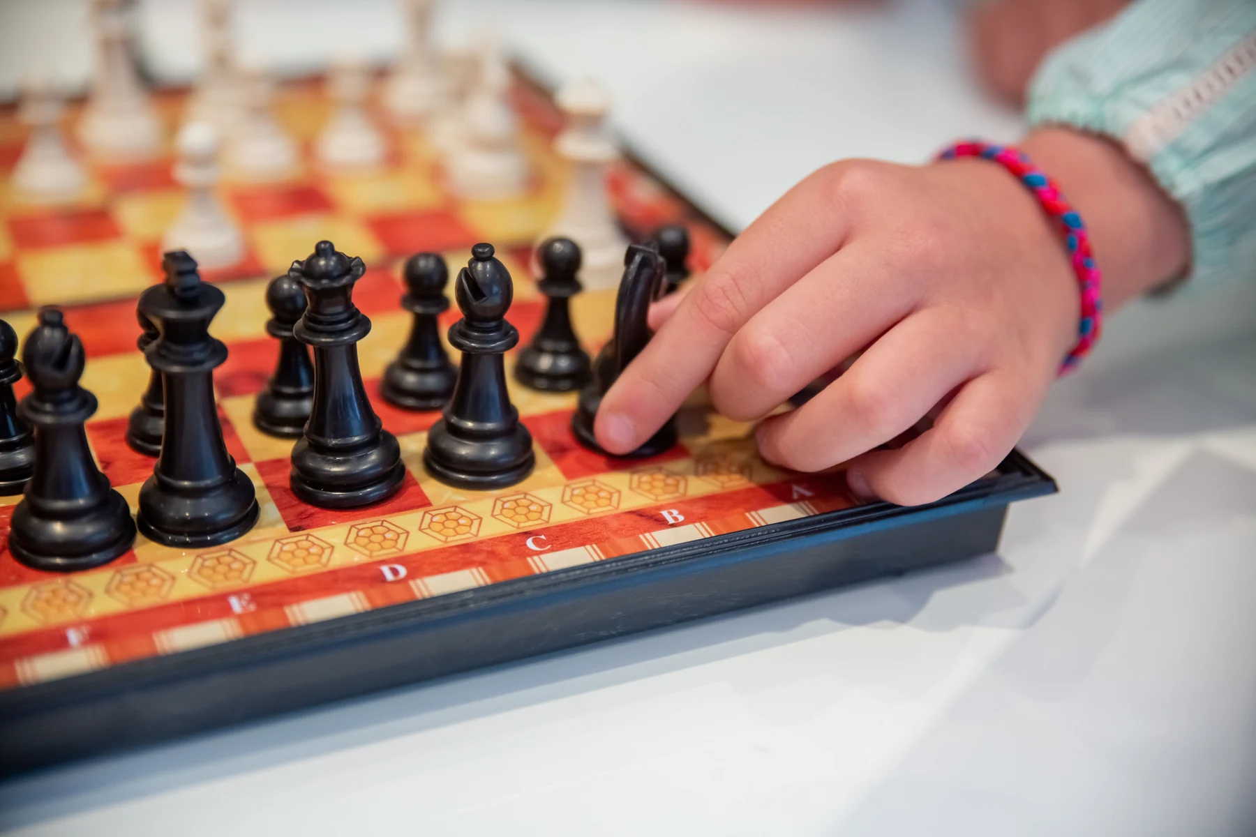 孩子在明亮的桌边用手移动棋盘上的棋子